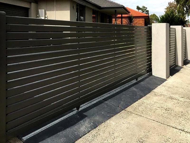 Custom fabricated sliding gate and slat fencing for residential home in a dark brown colour.