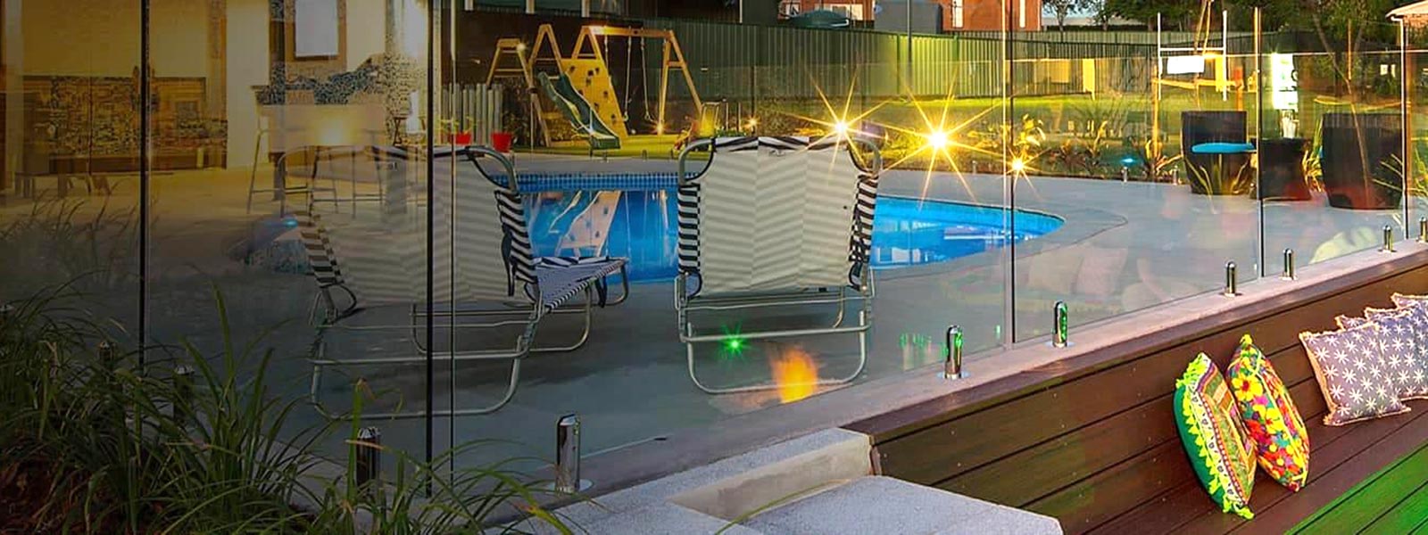 Evening photo of a swimming pool with frameless glass fencing