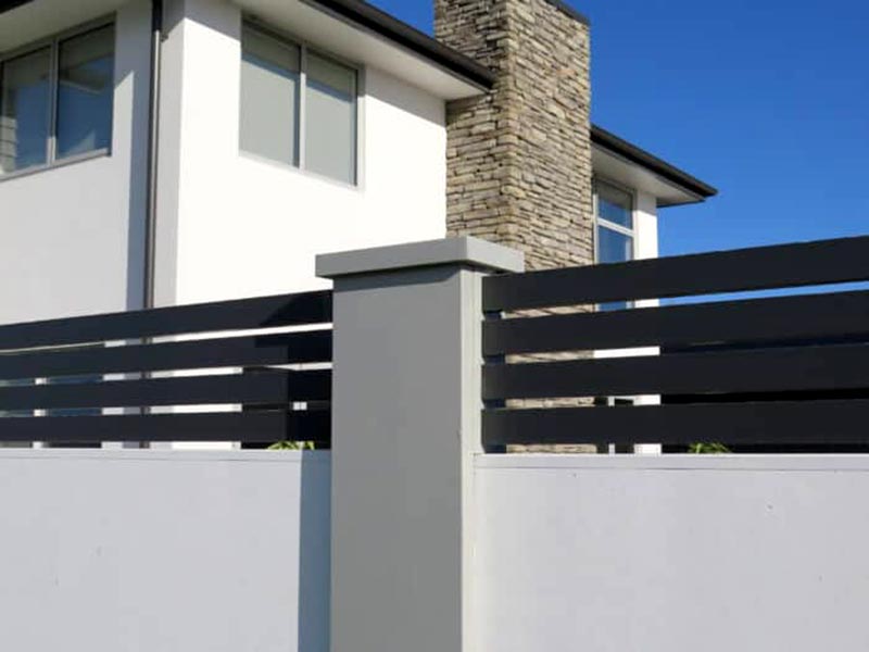 Dark grey pillar infill slat fencing on a white rendered masonry fence