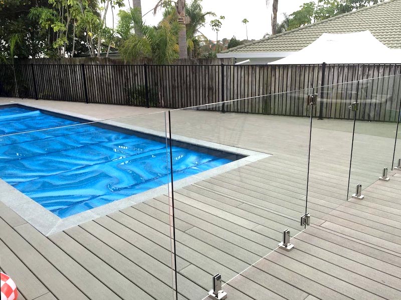 Frameless glass pool fencing around a residential pool deck